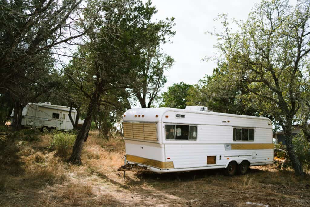 Vintage camper trailers set amidst trees in a peaceful Texas forest scene.